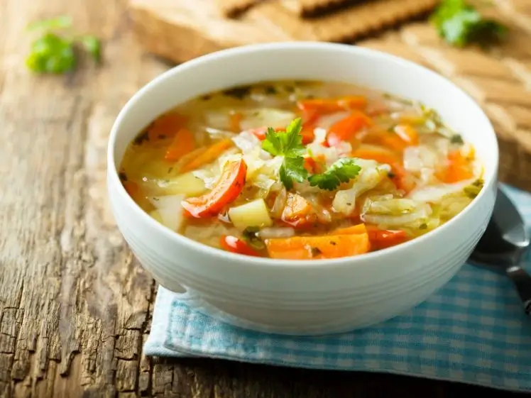 Semangkuk sayur sop bening dengan wortel, kentang, buncis, dan taburan bawang goreng