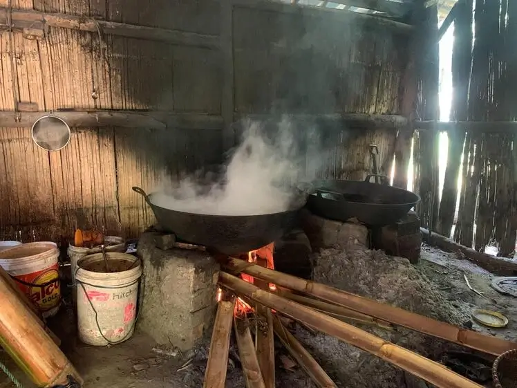 Palm sugar being cooked in a large wok over a wood fire